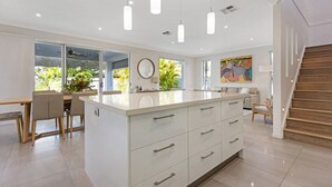 A modern kitchen with a central island, white cabinetry, and pendant lighting. - The Art House @ Beachside (Yaroomba)