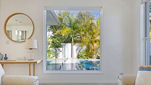 A modern living room with a large window, a round mirror, and two sofas. - The Art House @ Beachside (Yaroomba)