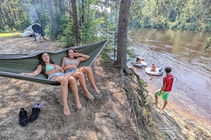 A hammock between two people, a river, and a person standing by the water. - Chalet en bois rond Poirier ! (Rivière-Rouge)