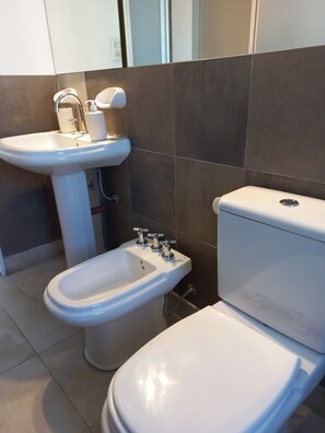 A bathroom with a white pedestal sink, a bidet, and a toilet. - Departamento Hermosa Vista Mendoza (Mendoza)