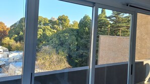 A room with large sliding glass doors leading to a balcony with a view of trees and buildings. - Departamento Hermosa Vista Mendoza (Mendoza)