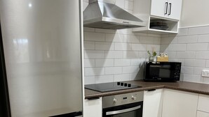 A modern kitchen with stainless steel appliances, white cabinetry, and a wooden floor. - Tuscan Villa in Myrtleford (Myrtleford)