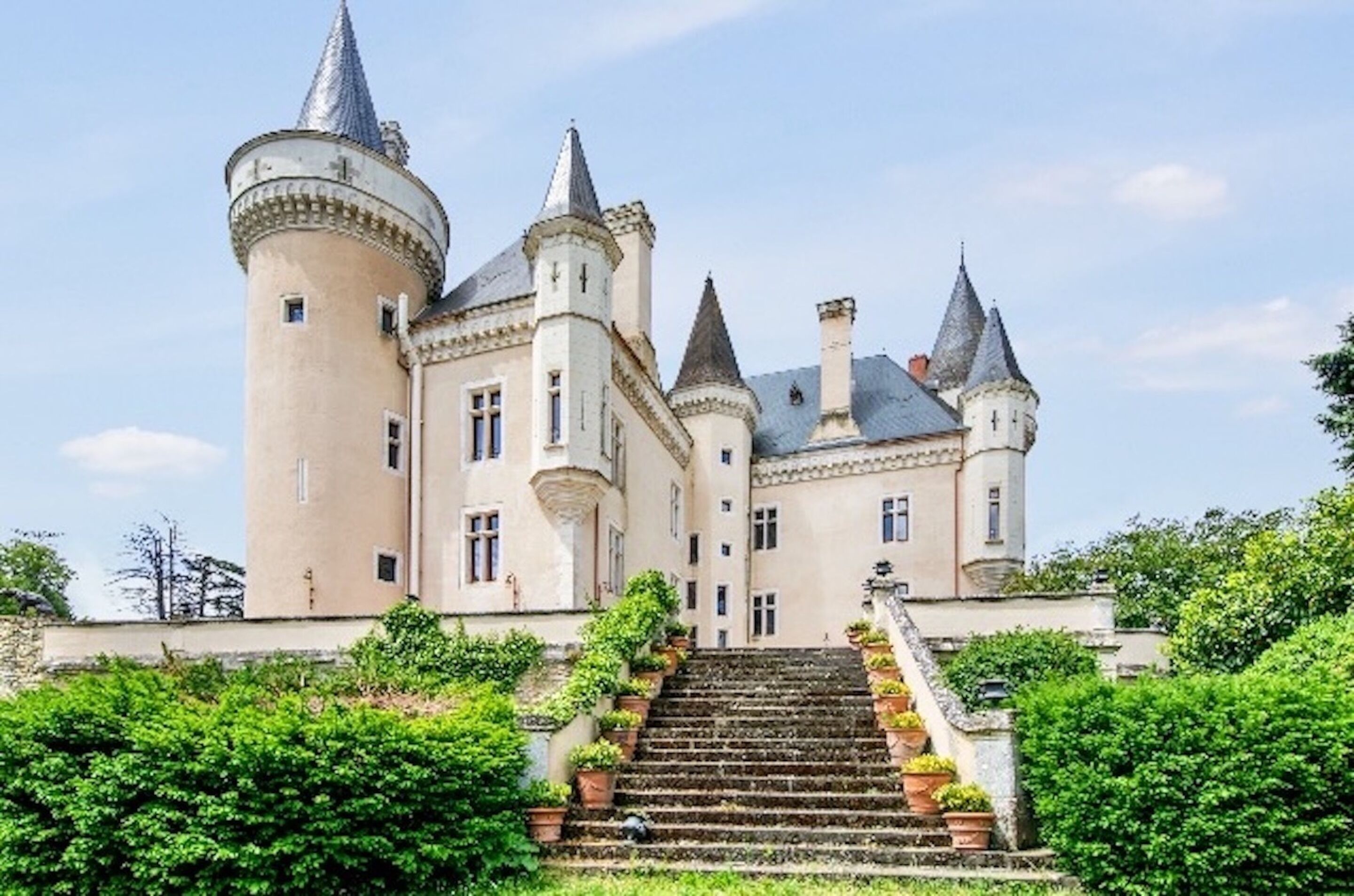 A castle with multiple towers, a central courtyard, and a staircase leading to the entrance.