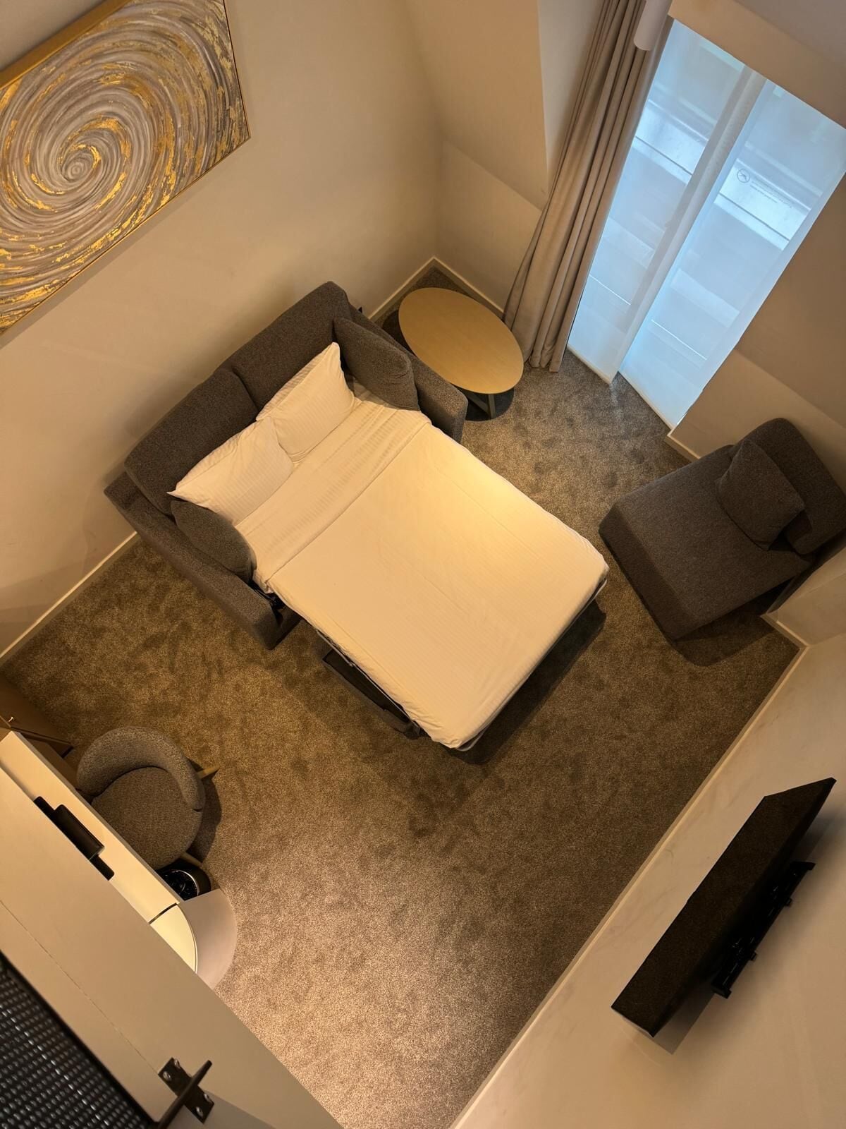 Ein modernes Hotelzimmer mit einem Bett, einem kleinen runden Tisch, einem Sessel und einer Couch.