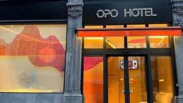 L’extérieur de l’hôtel OPO se distingue par sa façade moderne, ses grandes fenêtres et son entrée imposante.