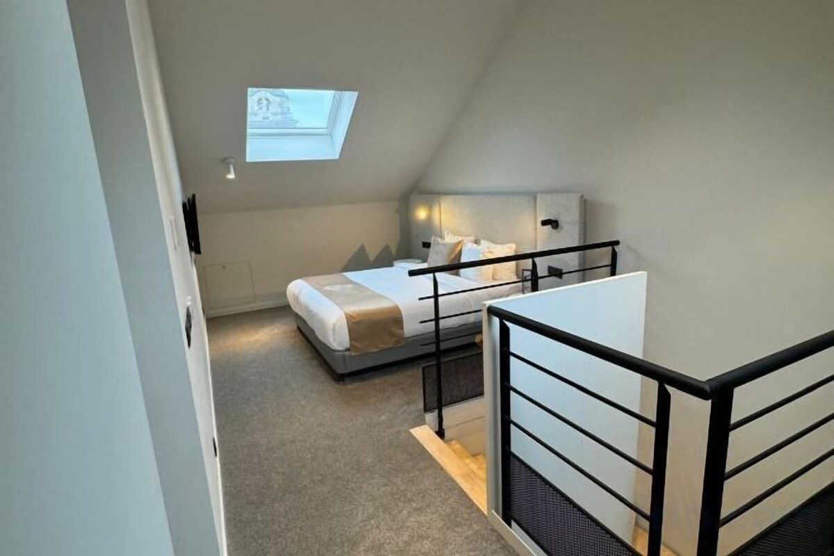 Un dormitorio con cama, escritorio, silla, ventana y tragaluz.