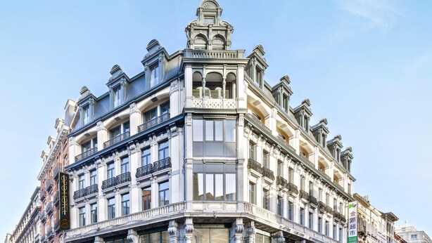Un edificio en esquina con detalles arquitectónicos ornamentales, incluyendo balcones y molduras decorativas.