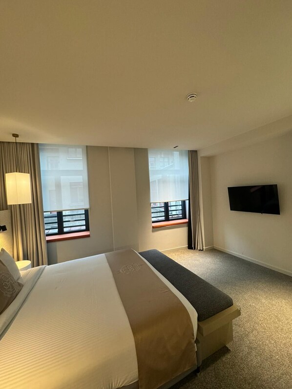 A hotel room with a large bed, a smaller bed, a TV mounted on the wall, and a window with a view of the outside. - OPO Hotel (Brussels)