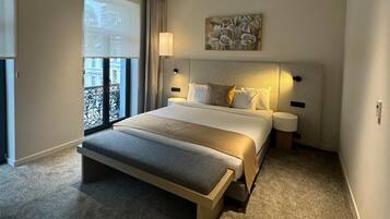Een moderne hotelkamer met een groot bed, nachtkastje, raam met gordijnen en uitzicht.