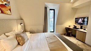 Una habitación de hotel moderna con una cama grande, un escritorio y un televisor.