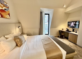 Una habitación de hotel moderna con una cama grande, un escritorio y un televisor.