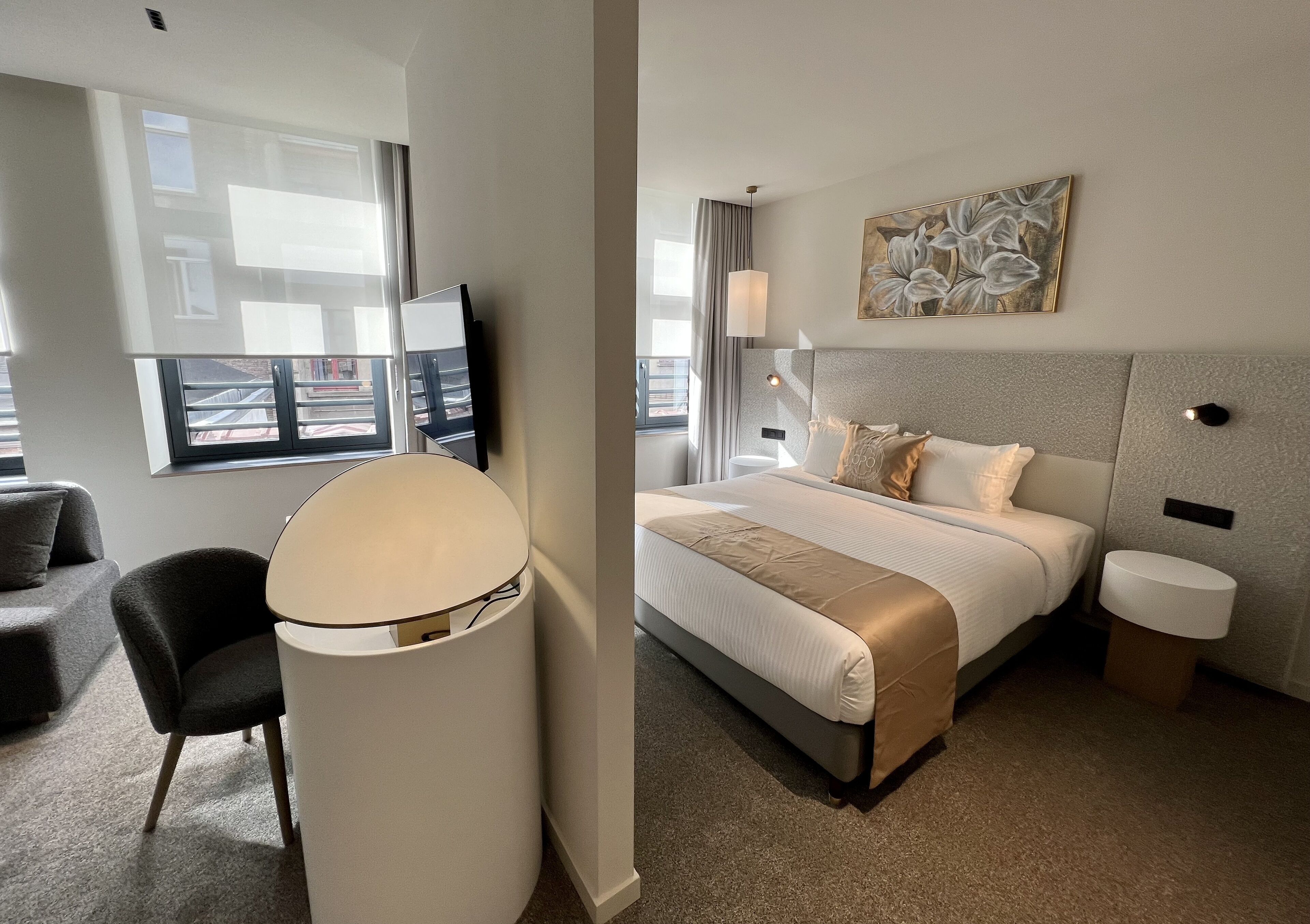 Ein Hotelzimmer mit Bett, Schreibtisch, Stuhl, Lampe und einem Bild an der Wand.