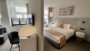 Ein Hotelzimmer mit Bett, Schreibtisch, Stuhl, Lampe und einem Bild an der Wand.