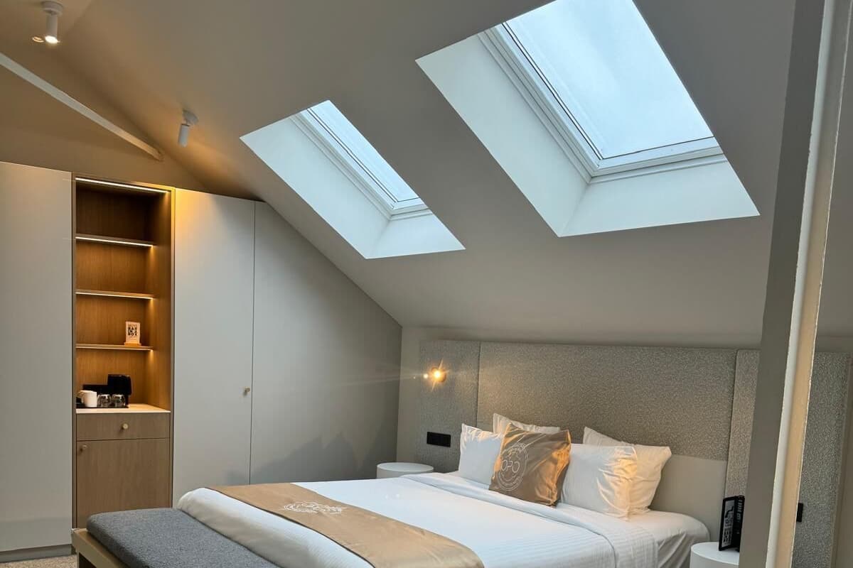 Une chambre à coucher moderne dotée d’une lucarne, d’une banquette intégrée et d’une table de chevet.