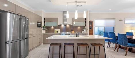 Una cocina moderna con una isla central, electrodomésticos de acero inoxidable y taburetes de bar.