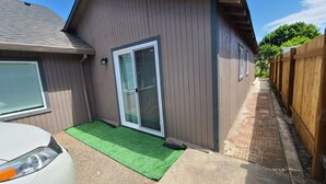 Een woonhuis met een schuifpui, een klein stukje kunstgras en een houten omheining.