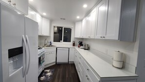 Een moderne keuken met witte kastjes, een ingebouwde oven, een vaatwasser en een raam boven de gootsteen.