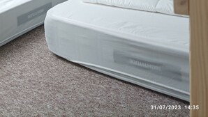 A bedroom with two mattresses, a wooden ceiling beam, and a white lattice structure. - Grand Studio 4 Couchages à 450m de la mer (Hermanville-sur-Mer)