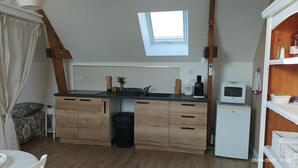 A compact kitchen with a built-in stove, a small refrigerator, and a window above the sink. - Grand Studio 4 Couchages à 450m de la mer (Hermanville-sur-Mer)