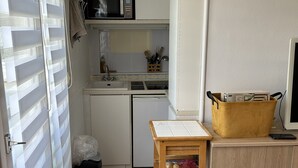 Cocina compacta con microondas, lavabo y armario de madera.