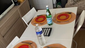 Una mesa de comedor con cuatro platos, dos botellas y una bandeja negra.
