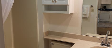 A bathroom with a bathtub, toilet, sink, and cabinets.