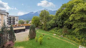 A hotel with a modern design, a garden area with a pathway, and a mountain view in the background. - Apartment BERGBLICK (Bad Reichenhall)