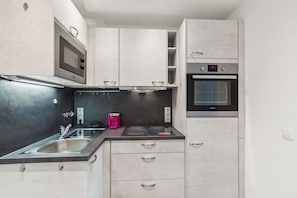 Eine kleine Küche mit Mikrowelle, Backofen und Kaffeemaschine.