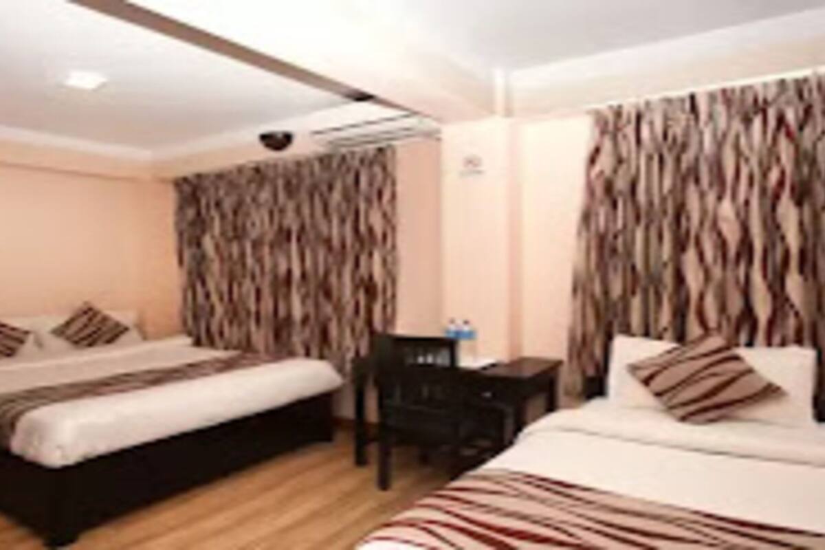 A hotel room with two beds, a desk, and a chair.