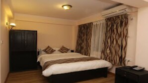 A bedroom with a bed, a wardrobe, an air conditioning unit, and a nightstand. - MeroStay 206 Hotel KU (Kathmandu)
