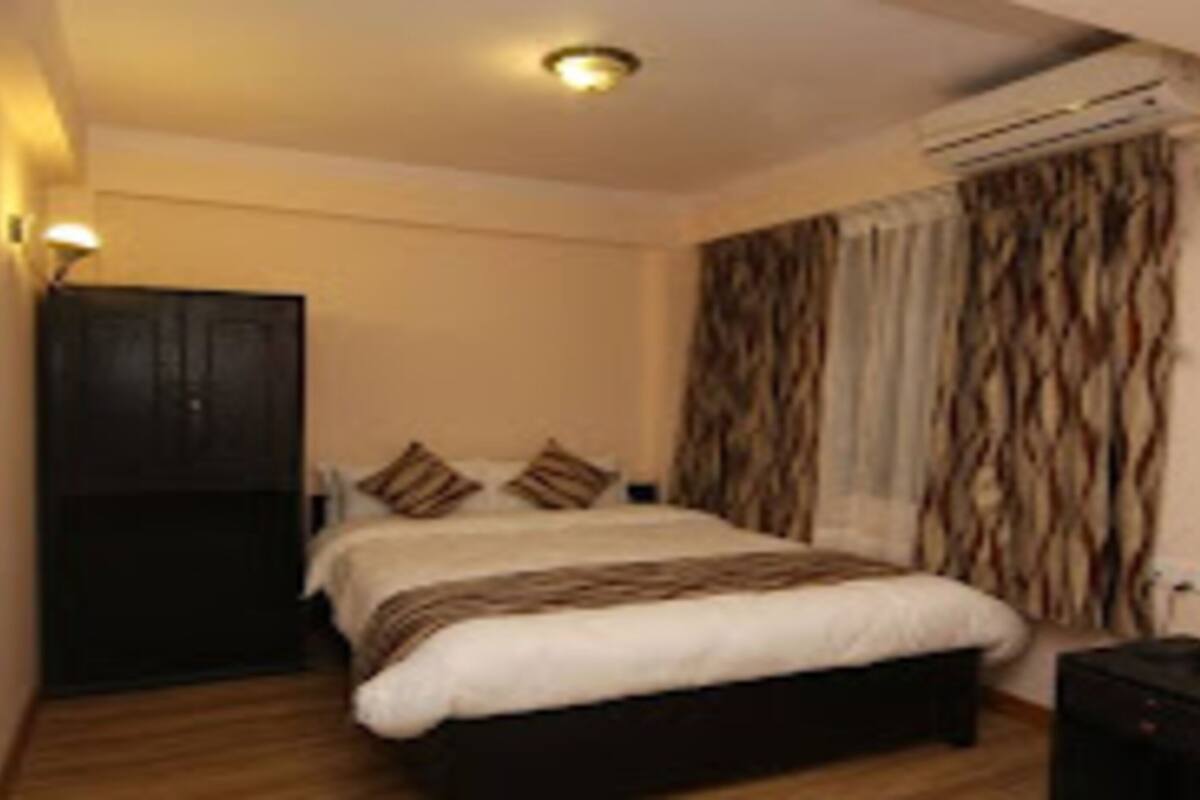 A bedroom with a bed, a wardrobe, an air conditioning unit, and a nightstand.