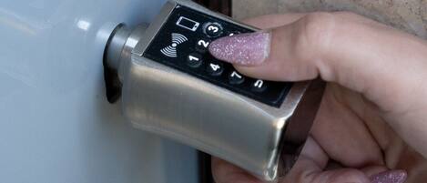 A hand using a keypad lock on a door.