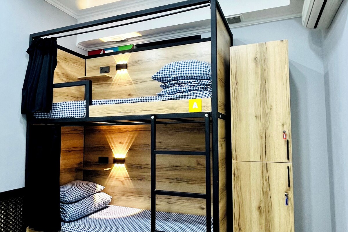 A bunk bed with a wooden finish, a wardrobe, and a wall-mounted air conditioner.