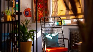 A cozy living room with a black metal shelf holding plants, a patterned rug, and a wooden floor. - People Hostel (Bishkek)