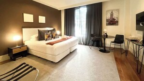 A modern hotel room with a large bed, a desk, and a chair.