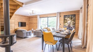 Un interior moderno con zona de comedor, sofás y chimenea.