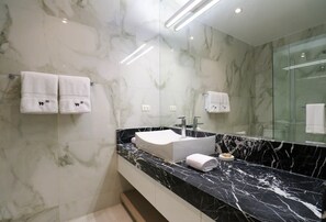 A modern bathroom with a marble wall, a black marble countertop, a white sink, and two white towels with a logo. - w* | Stunning House in the Heart of Barranco (Barranco)