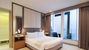 Une chambre d’hôtel moderne avec un grand lit, une table de chevet, un miroir et une vue sur l’extérieur grâce à de grandes fenêtres.