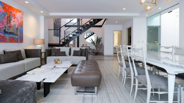 Un salon moderne comprenant un canapé, une table basse et un coin repas avec une table et des chaises.