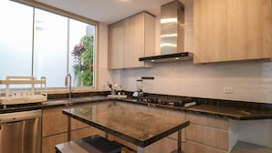 Une cuisine moderne dotée d’un grand îlot central, d’appareils électroménagers en acier inoxydable et de meubles de rangement en bois.