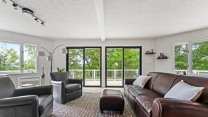 Un salon moderne avec un canapé en cuir marron, un fauteuil noir et un tapis à motifs.