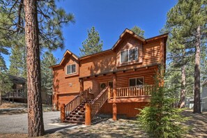 A two-story log cabin with a front porch and a staircase leading to the entrance.