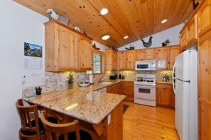 A kitchen with wooden cabinets, granite countertops, a built-in oven, and a refrigerator.