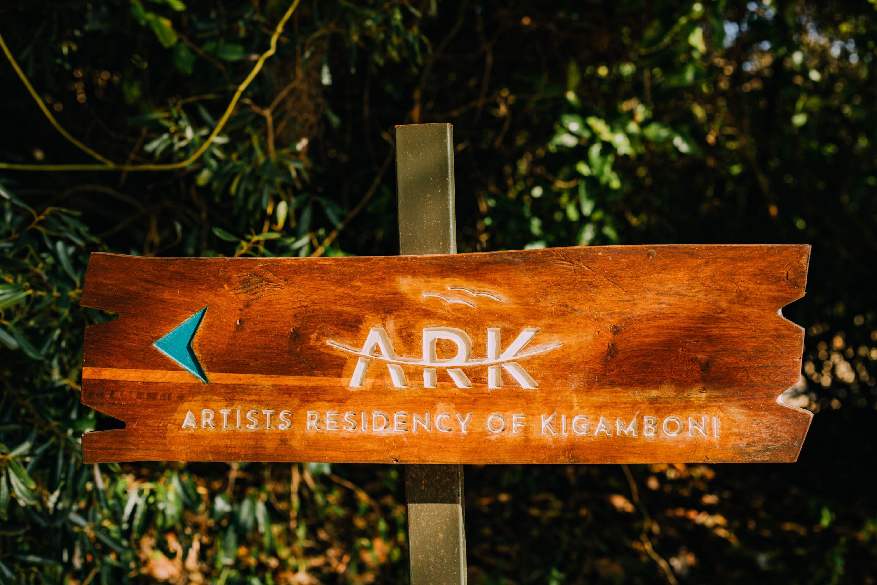 Un letrero de madera con el texto 'ARK Artists Residency of Kigamboni'.