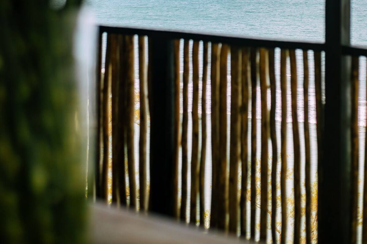 A view of the ocean through a window with a bamboo fence.