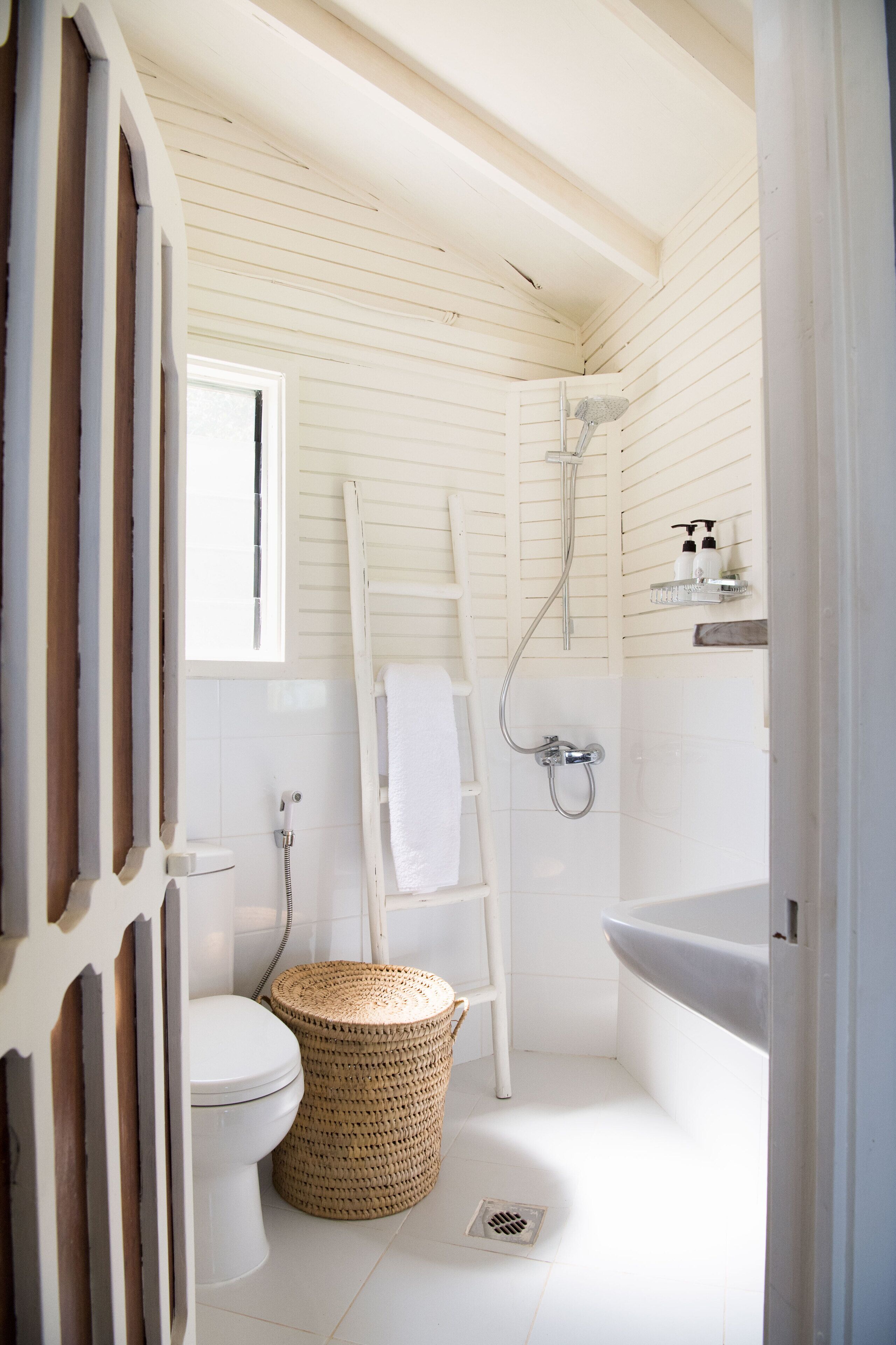 Ein kleines, weißes Badezimmer mit Toilette, Dusche und Waschbecken.