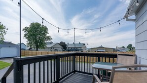 Eine Holzterrasse mit Tisch und Stühlen, mit Blick auf eine Wohngegend mit Häusern und einem Baum.