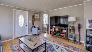 Ein Wohnzimmer mit Fernseher, Sofa, Couchtisch, Bücherregal und einem gemusterten Teppich.