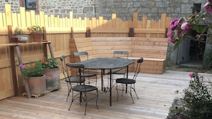 Eine Terrassengruppe im Freien mit Holztisch und -stühlen, umgeben von einem Holzzaun und Blumentöpfen.
