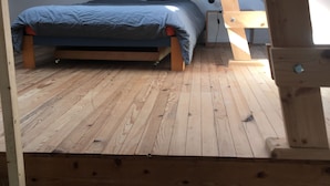 Ein Schlafzimmer im Loft-Stil mit Holzboden, einem Bett mit grauer Bettwäsche, einem Nachttisch und einem kleinen Tisch.